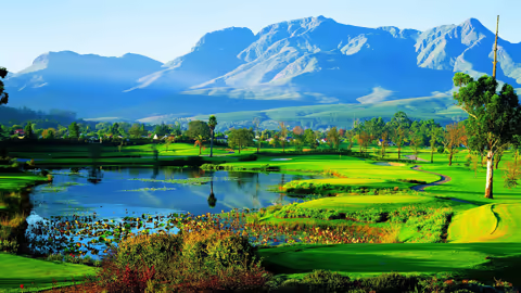 Stunning golf course view with lush greens and majestic mountains in the background, showcasing Africa's natural beauty.
